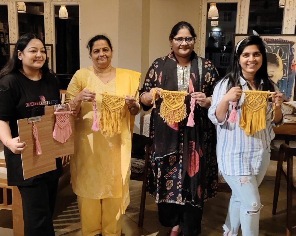 Beginner macramé workshop in Goa with participants holding handmade wall hangings