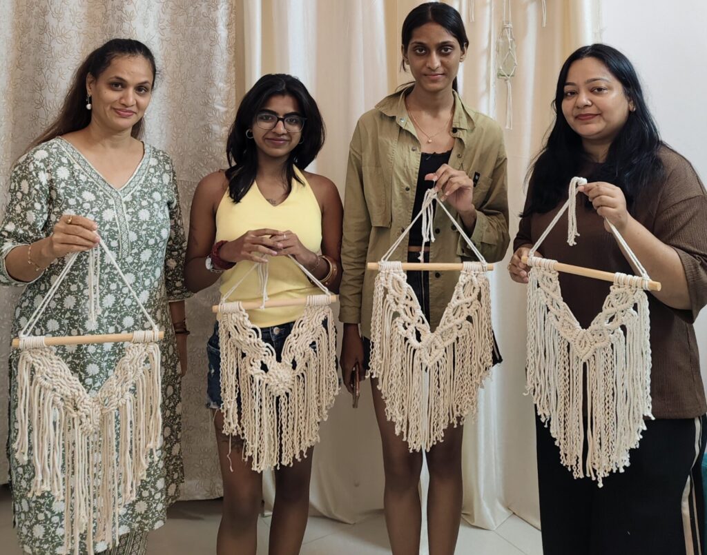 Participants proudly holding their handmade macramé wall hangings after completing a beginner-friendly macramé workshop in Goa.