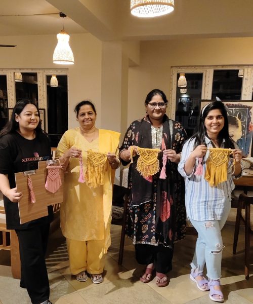 Beginner macramé workshop in Goa with participants holding handmade wall hangings